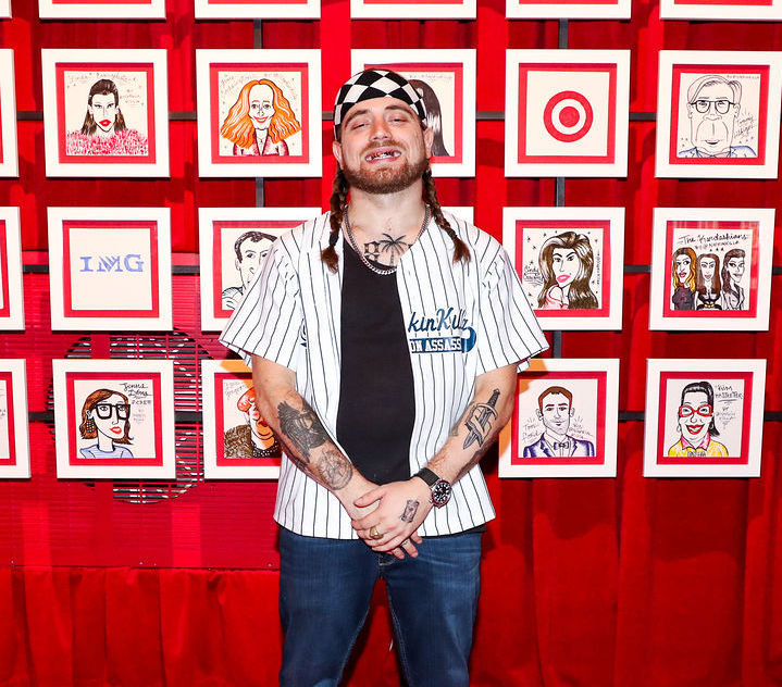 Napkin Killa smiles wide in front of his portraits of celebrities at Target's 2016 NYFW event.  