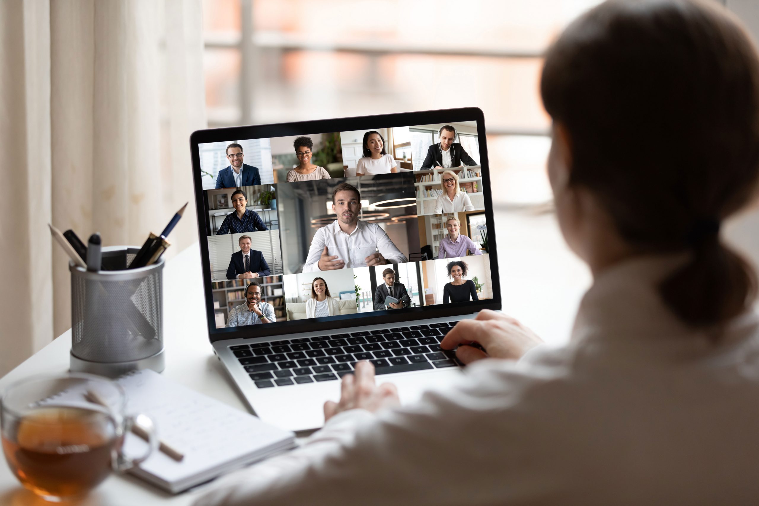 Woman on a computer in a virtual meeting with many other people on screen