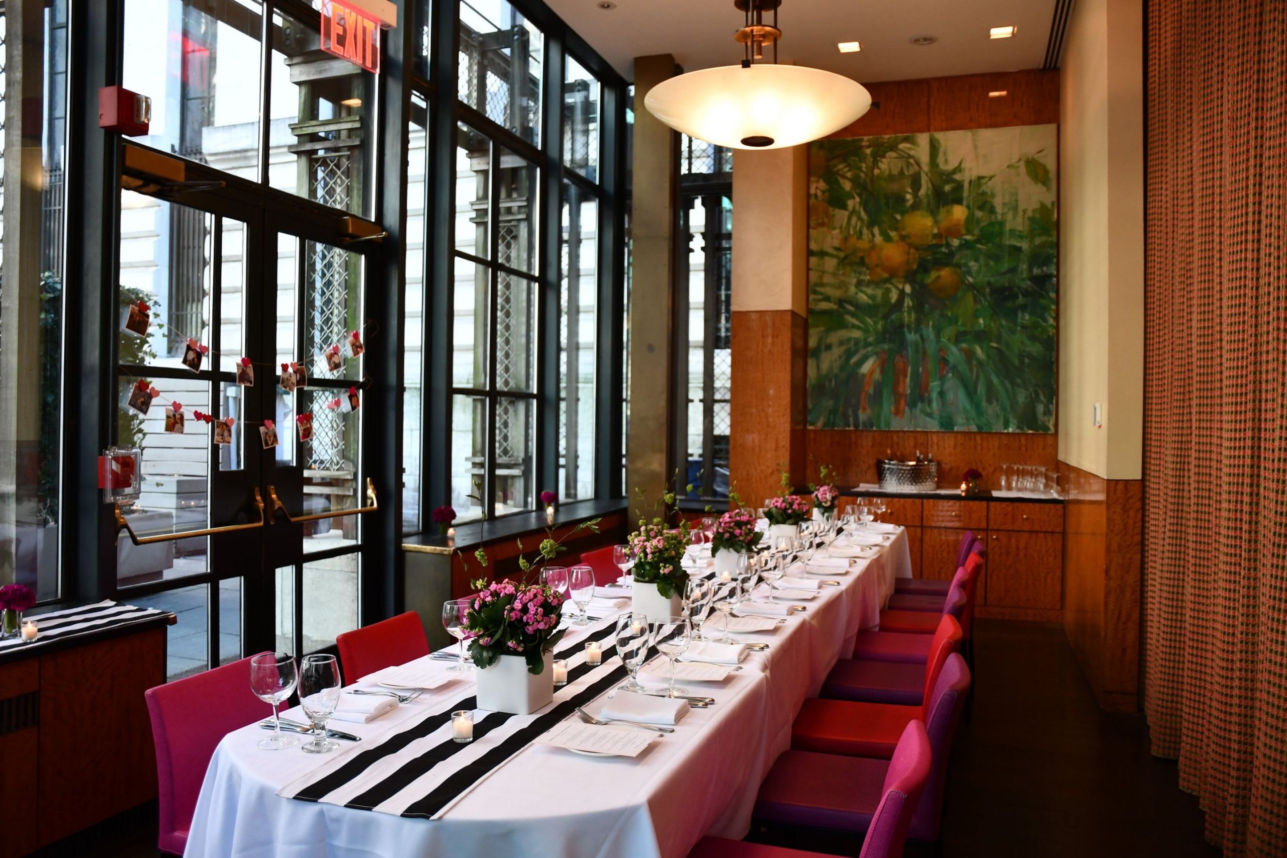 Long dining table with black and white runner with pink chairs and pink floral arrangements