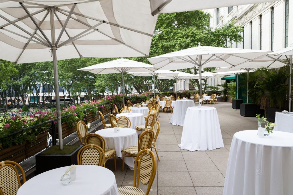 Round tables with white linens under white umbrellas