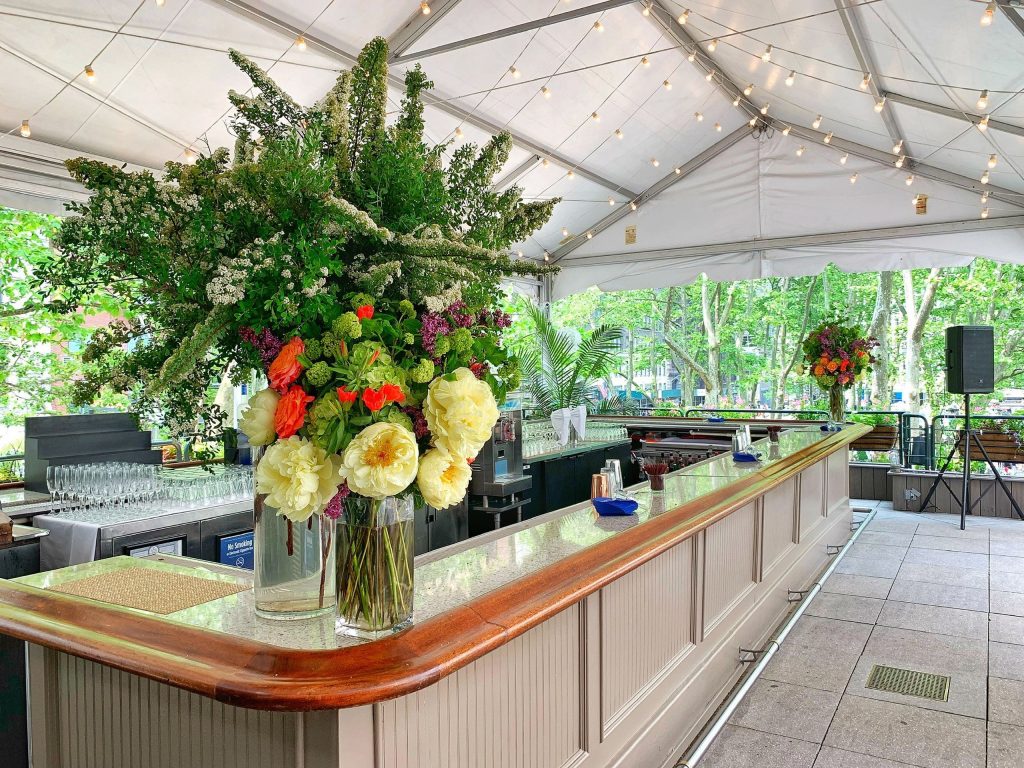 Outdoor bar under a covered tent with a large floral bar arrangement