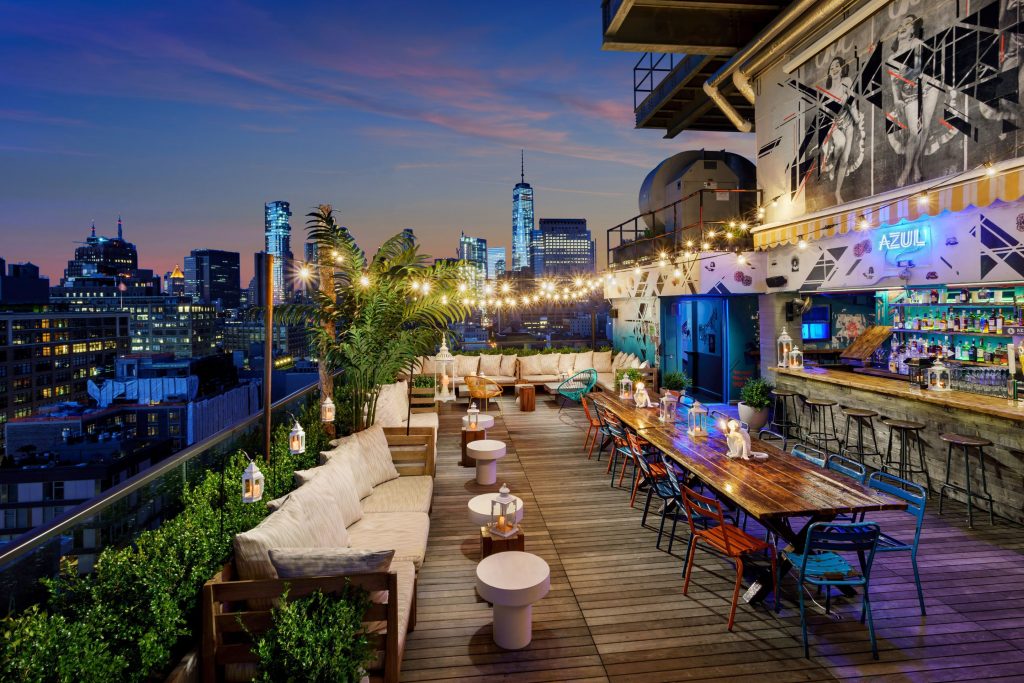 Rooftop bar with view of NYC skyline with wooden floors and string lights