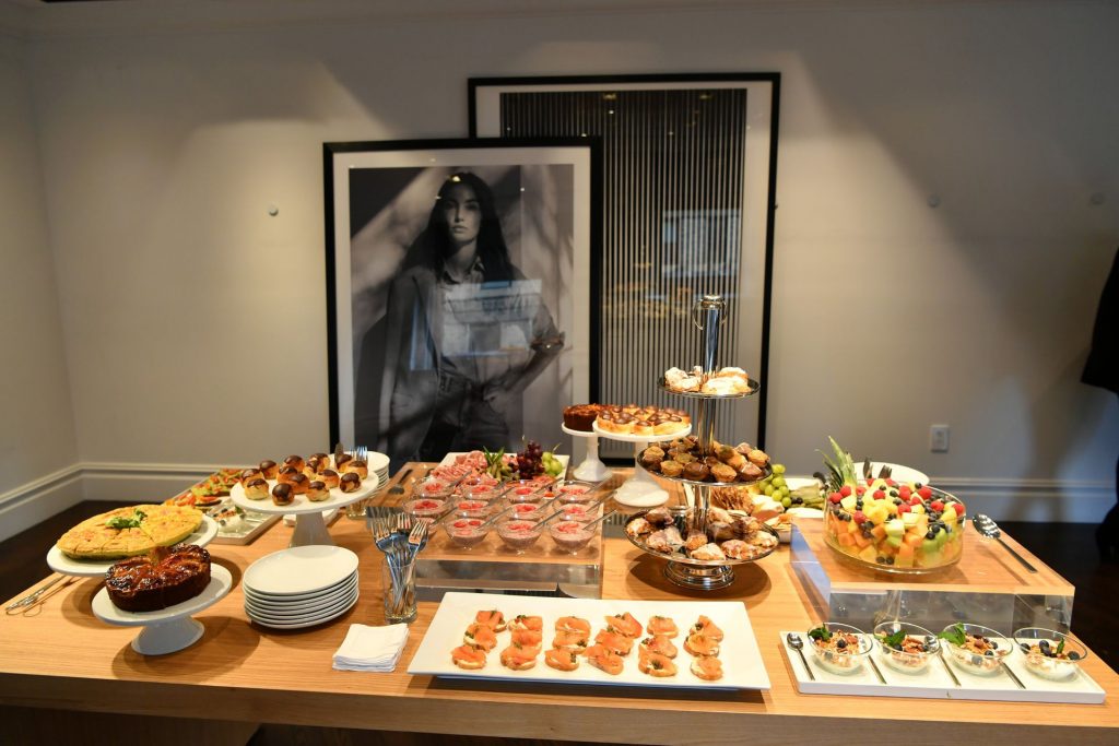 A spread of brunch food items including a large fruit bowl and pastries