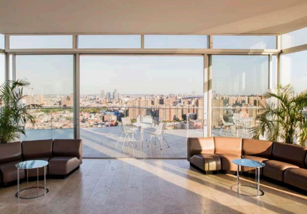 An indoor and outdoor rooftop setting with view of downtown NYC