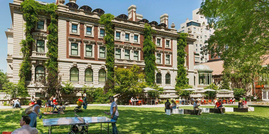 Open lawn with seating and ping pong in front of large traditional building