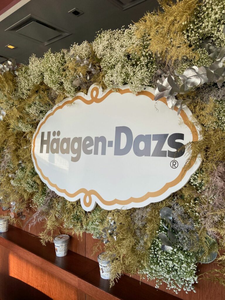 A lrage Häagen Dazs sign surrounded by green and silver foilage
