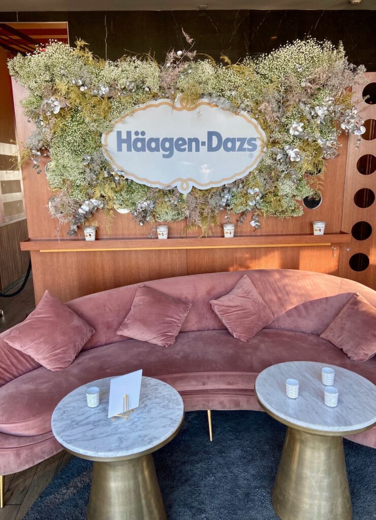 A velvet pink couch in front of a Häagen Dazs sign