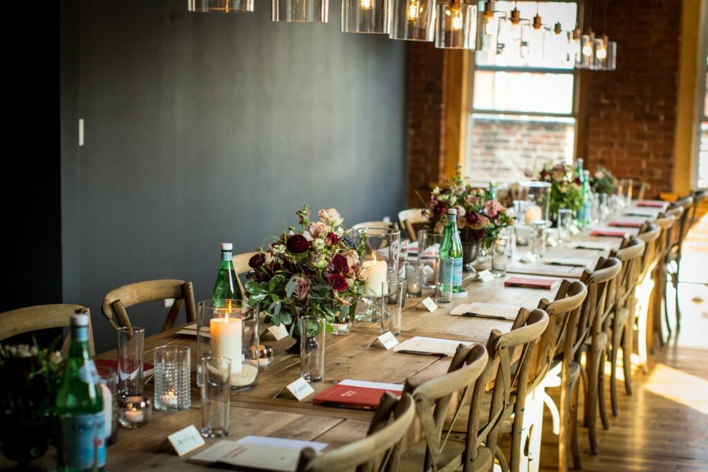 Long wooden Tables adorned with flower arrangements and wooden chairs