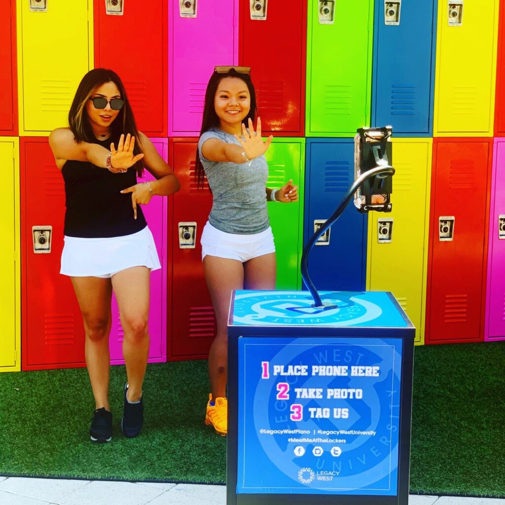 Two girls in front of a locker photo backdrop taking a photo