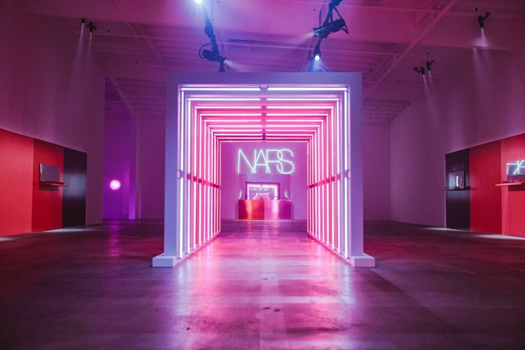 A neon tunnel installation that says "NARS" at the end