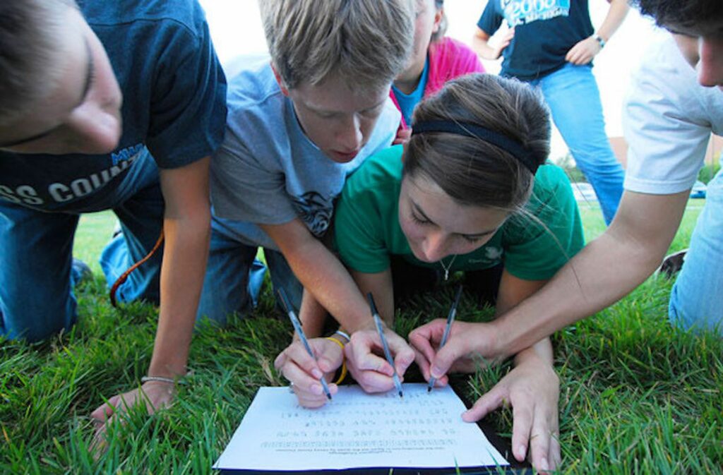 People huddled around a piece of paper writing 