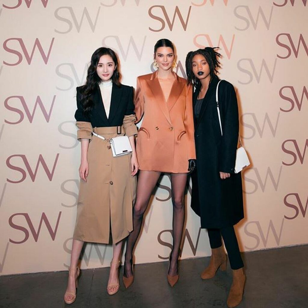 Three women at fashion week in front of a step and repeat