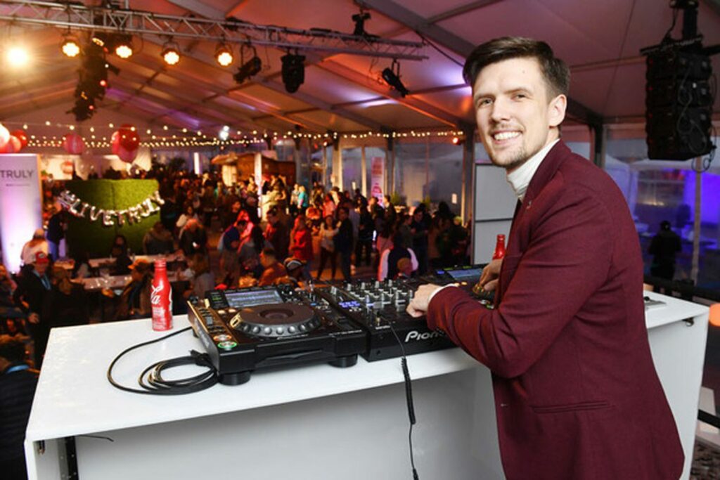 A DJ looking over his shoulder, DJ'ing  to a crowd