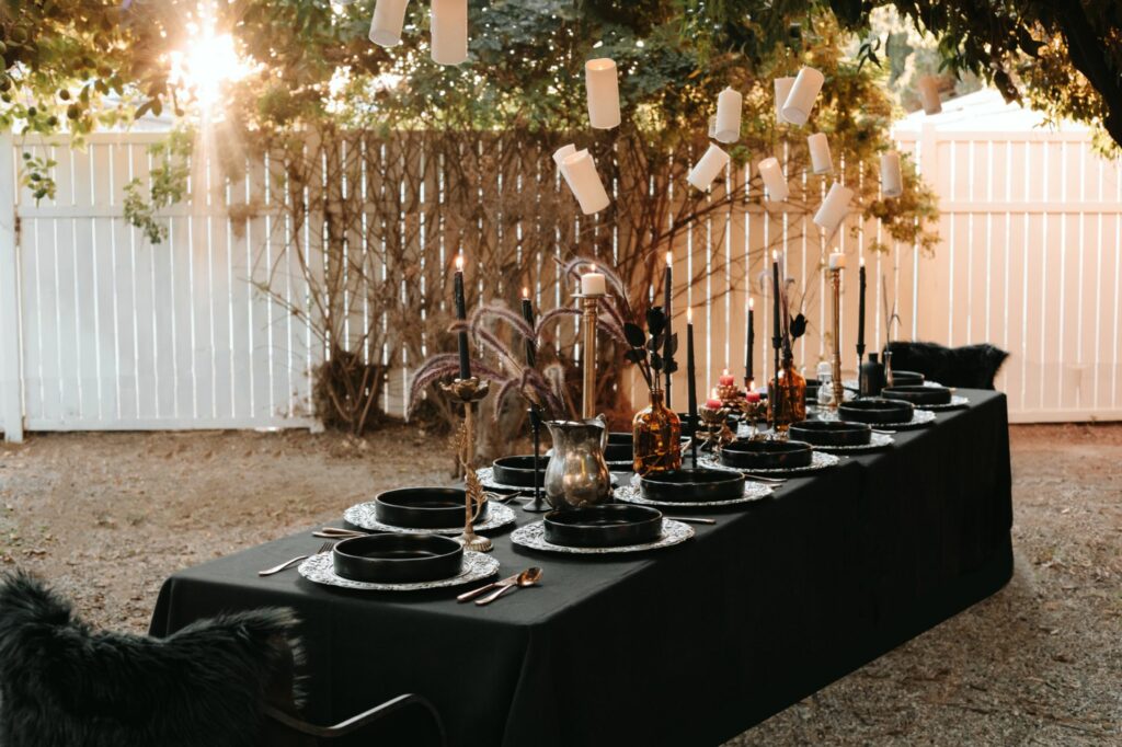 A fall table setting of a long table with black tablecloth and black candlesticks