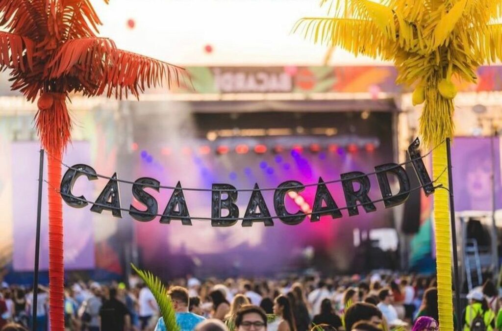 Festival scene with colorful palm trees and a banner that says "Casa Bacardi"