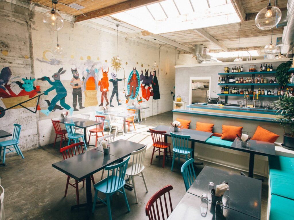 Restaurant with skylight, black square tables and colorful chairs 