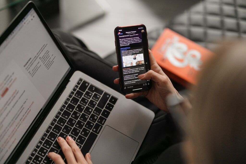 Person on a computer and looking at a cell phone