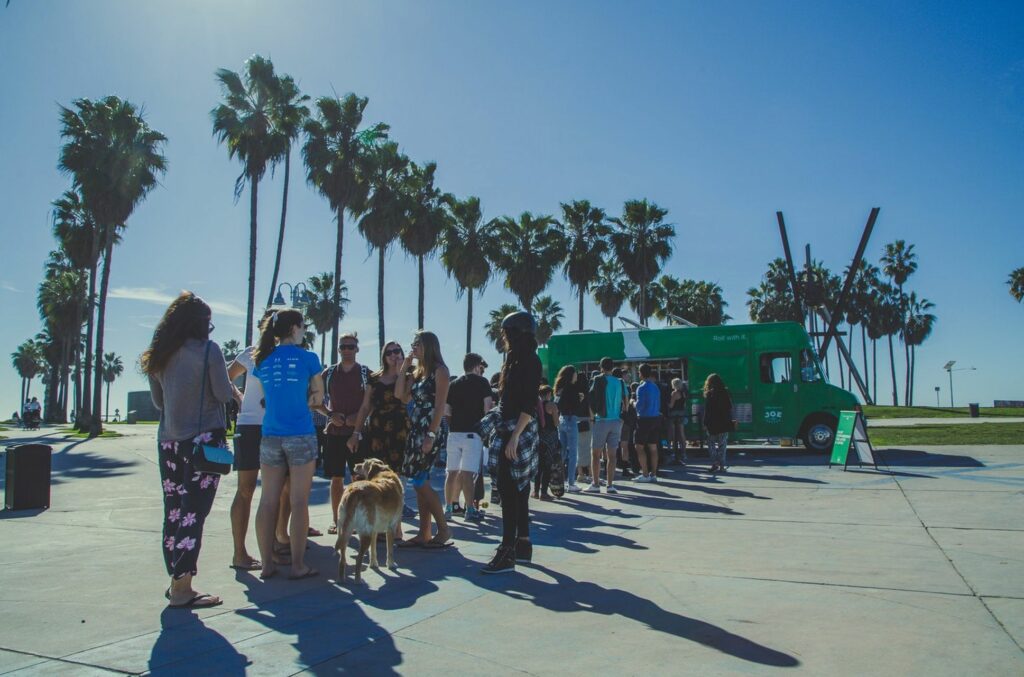 A line of people waiting in front of a green truck