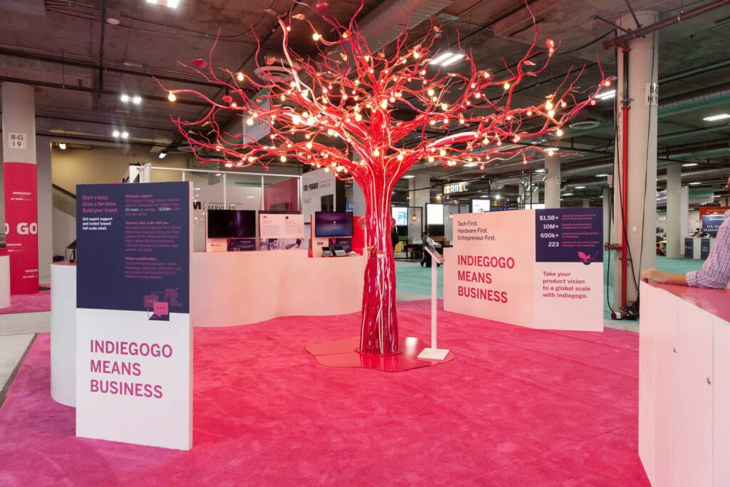 Large booth at a conference with a light up pink tree in the middle