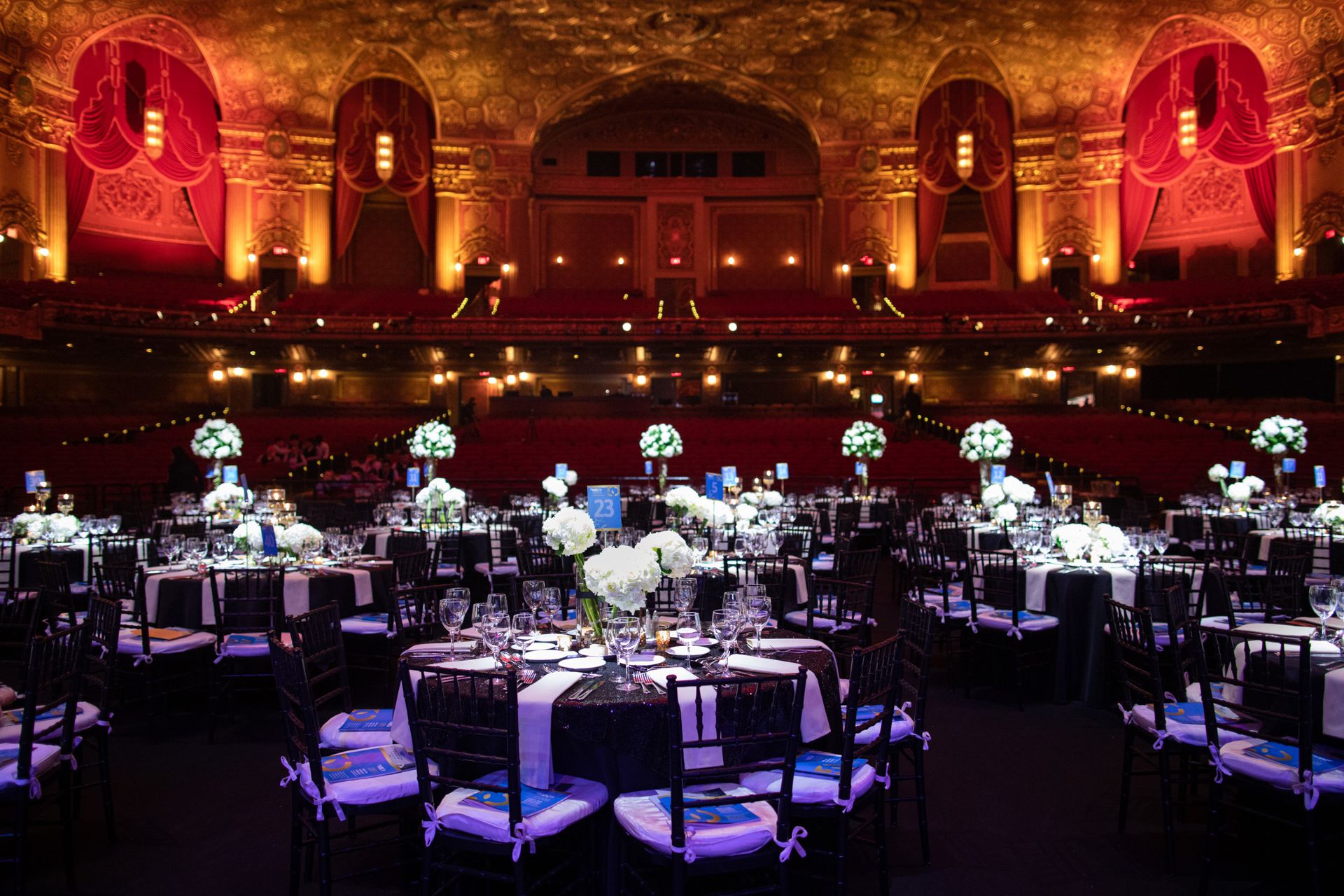 Large ornate room with many round tables with centerpieces