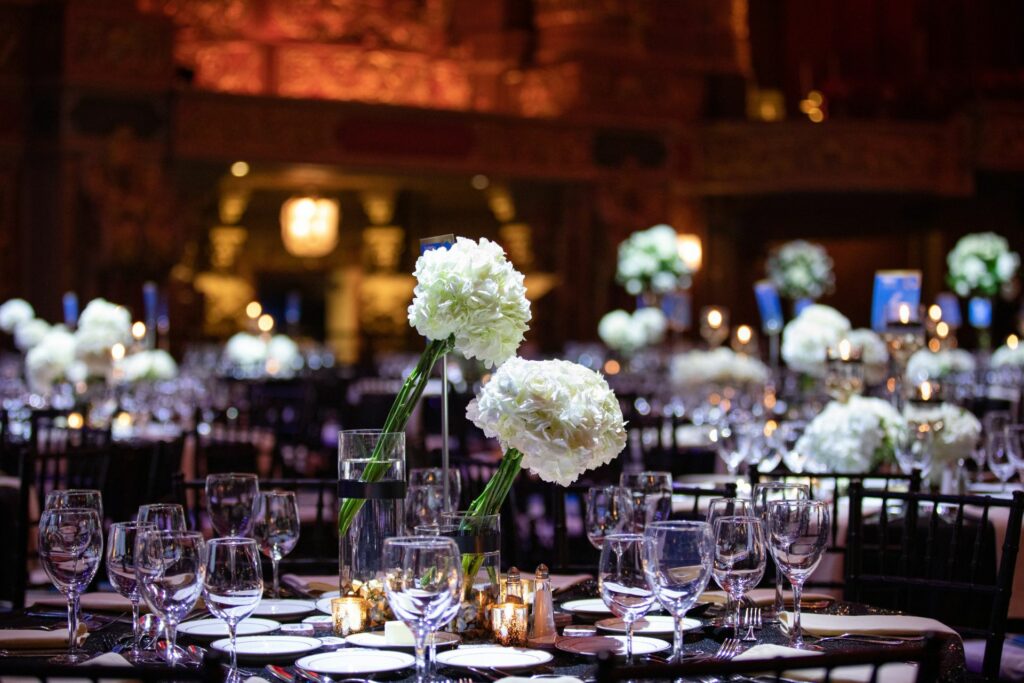 Round tables at a large event set with plates and flowers