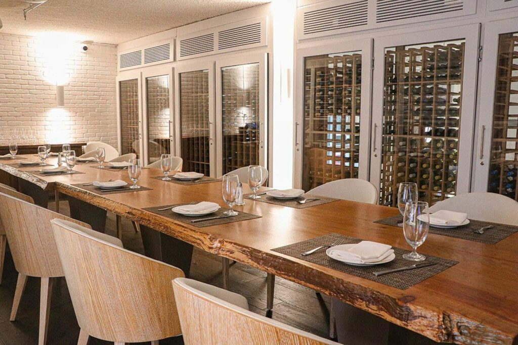 A long wooden table in a private dining room next to a wine cellar