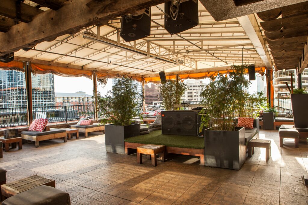 A covered rooftop bar with several lounge setups 