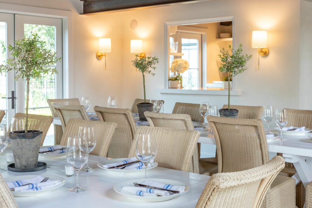 Inside a restaurant with white tables with wicker chairs