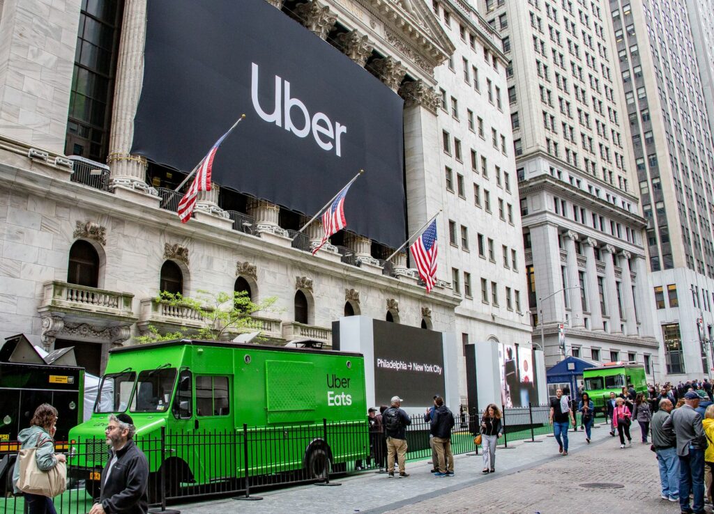 A green truck outside of a building with a large sign that says "Uber"