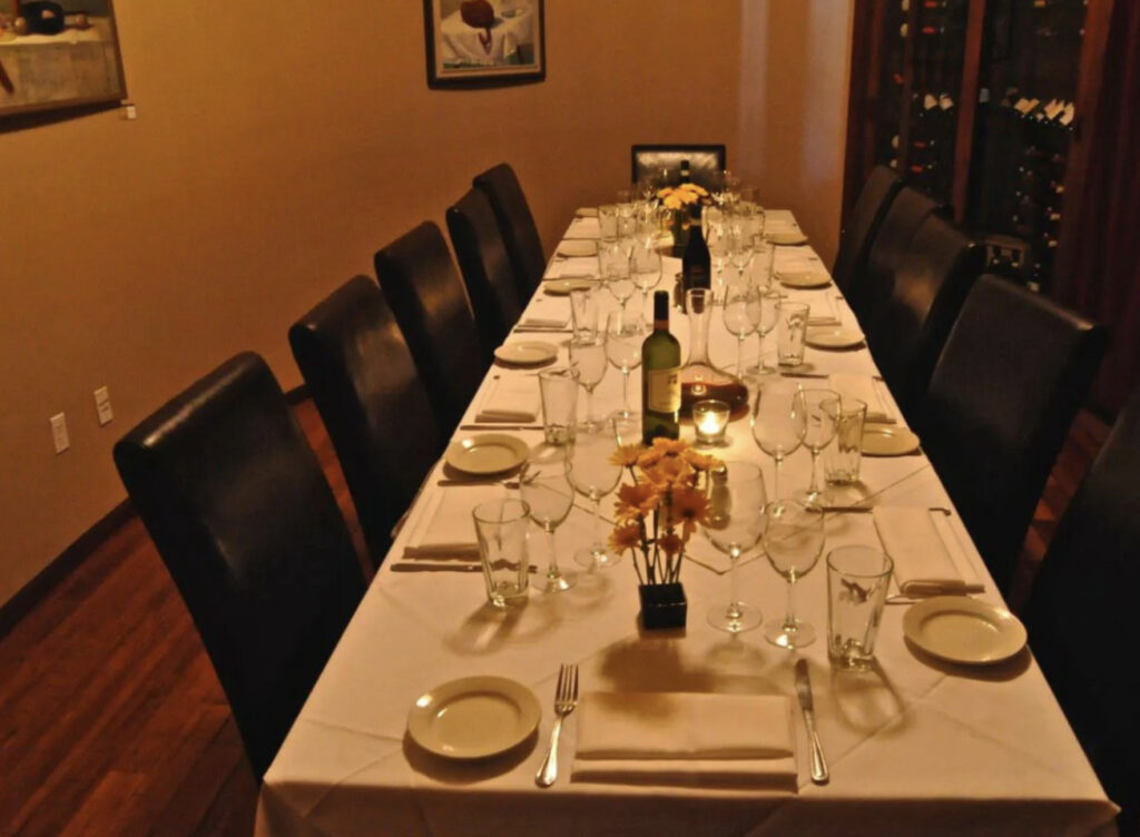 Long dining table with white tablecloth in dimly lit room