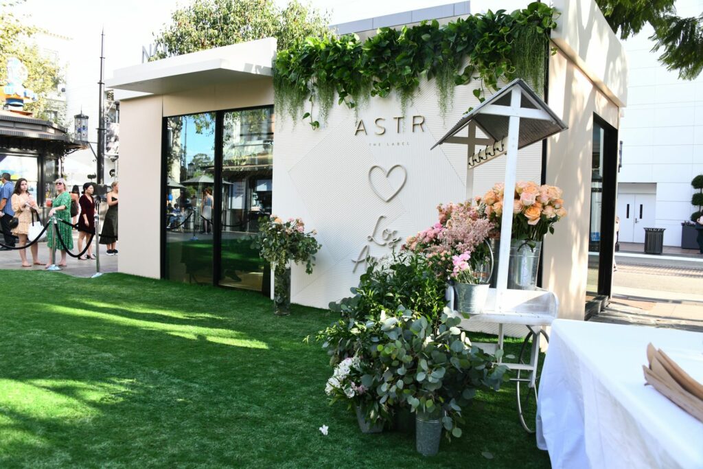A branded booth outside on a green turf next to a flower cart