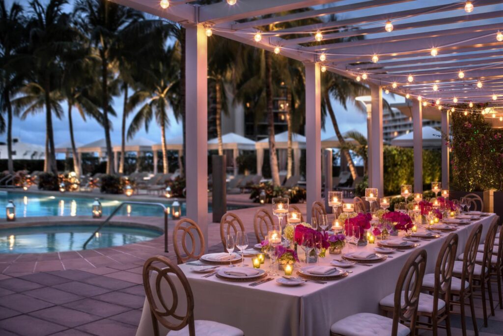A long table with candle light and flowers overlooking a pool