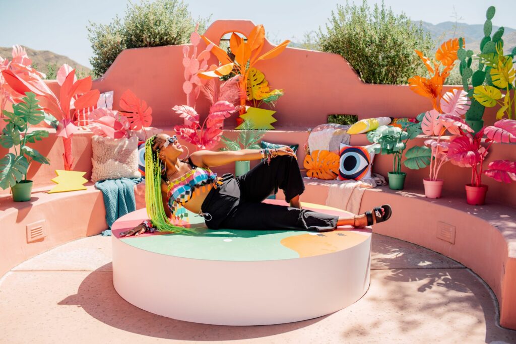 A woman lying in the sun posing for a photo among a brightly colored backdrop