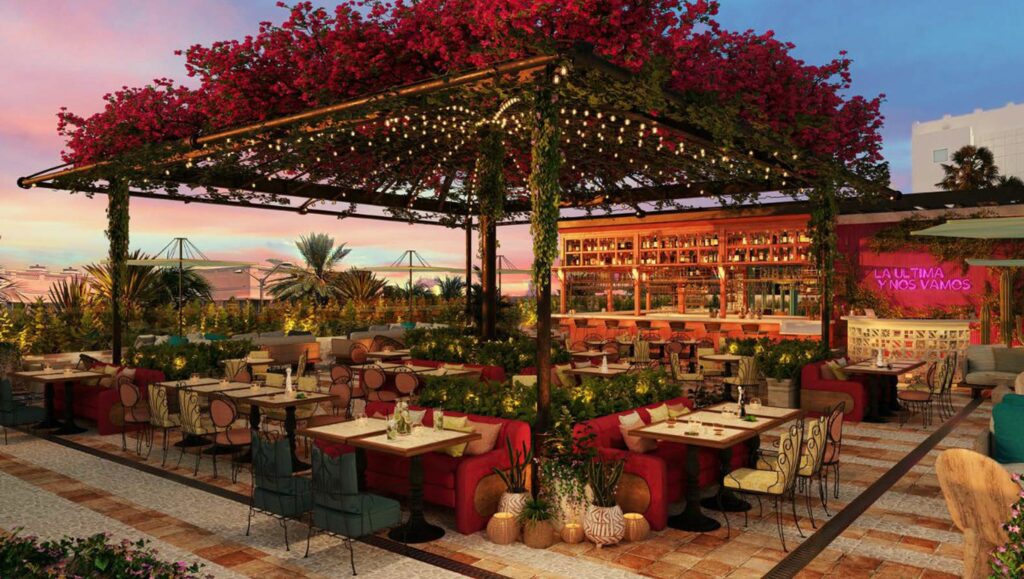 A large gazebo covered in flowers surrounding by tables and chairs