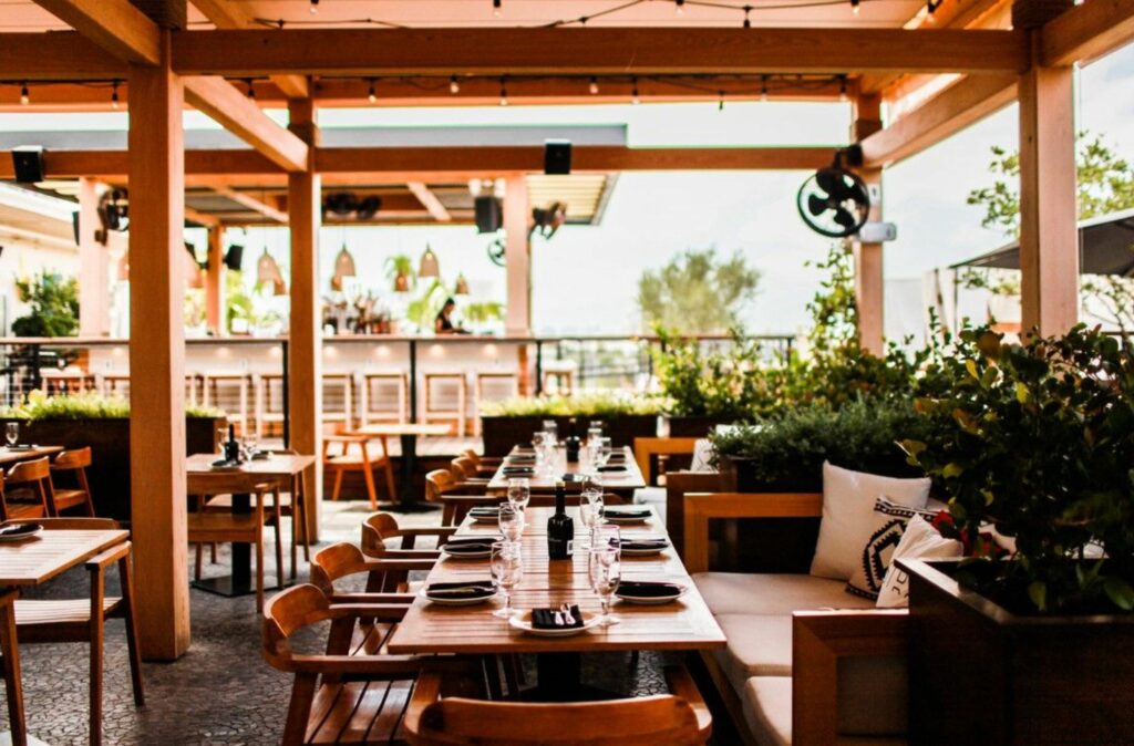 An outdoor restaurant with tables and chairs under a gazebo awning