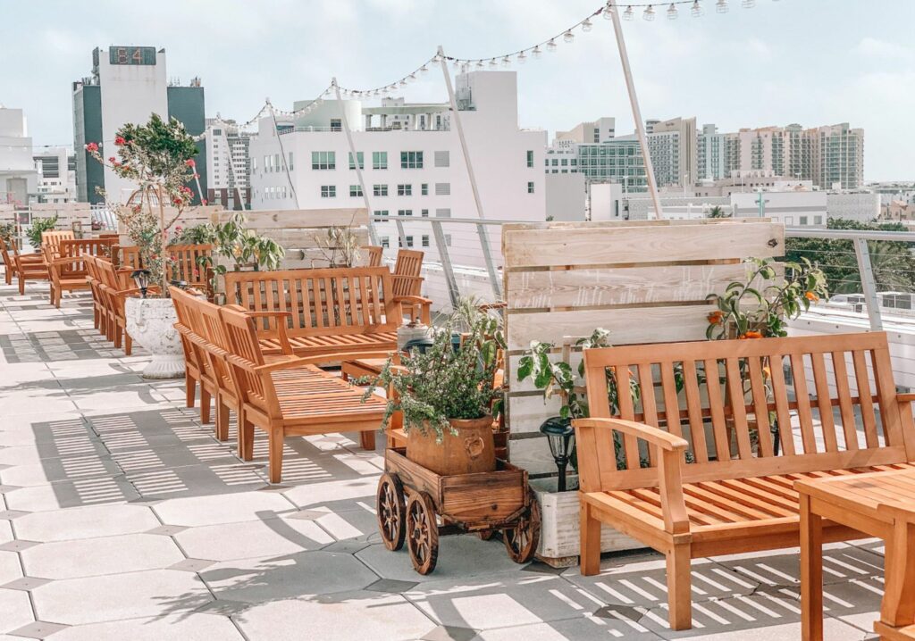 A city rooftop bar with wooden benches, tables, and dividers