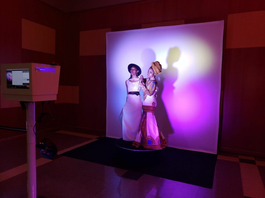 Two women getting their picture taken by a photo booth