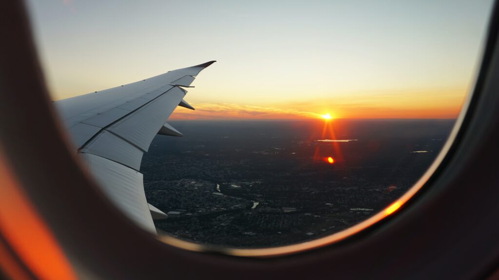 A plane wing and sunset from inside a plane