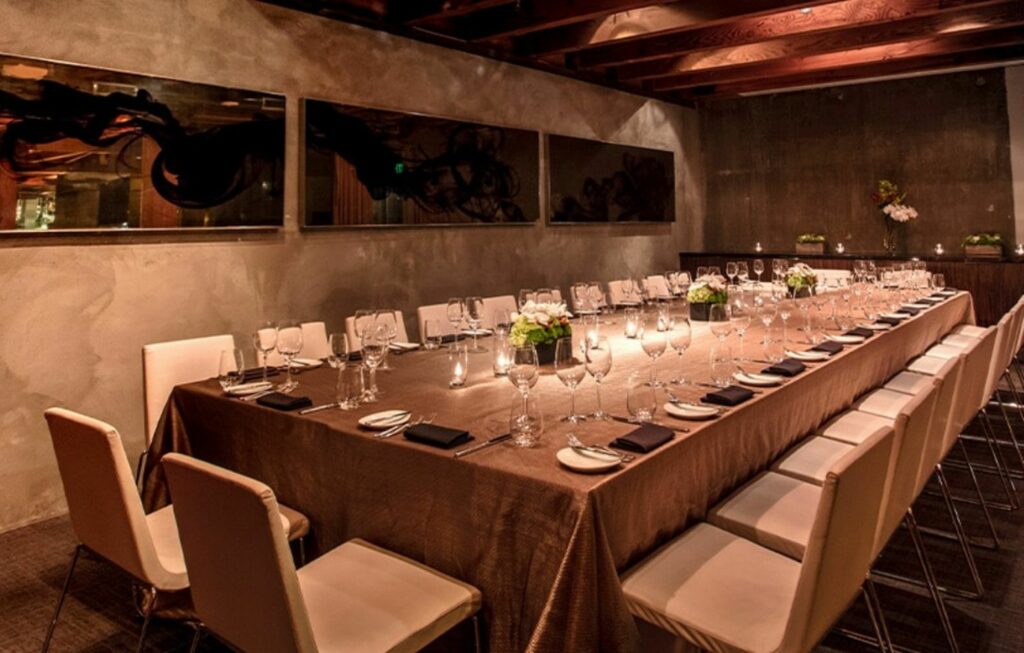 Large dining table set up in a room with moody lighting 