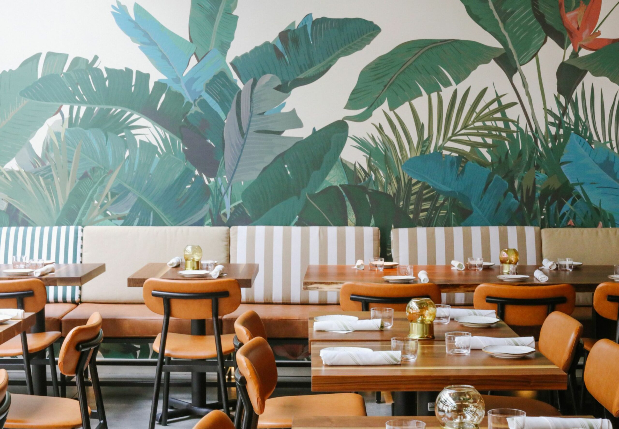 Restaurant with wooden chairs and palm leave print wallpaper