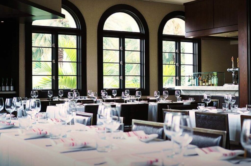 A restaurant dining room set with white tablecloths and glassware