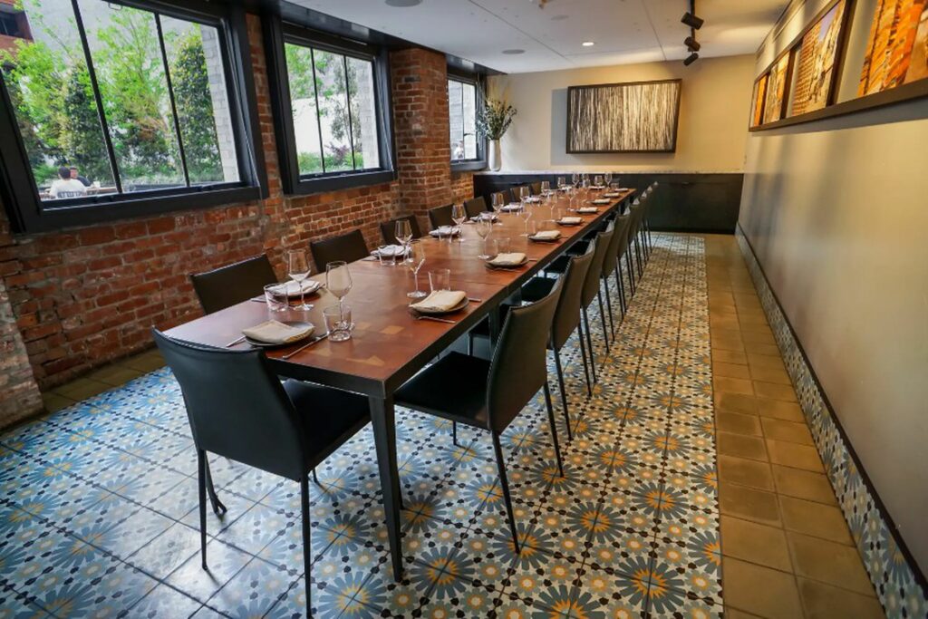 A long wooden dining table in a room with a colorful tiled floor