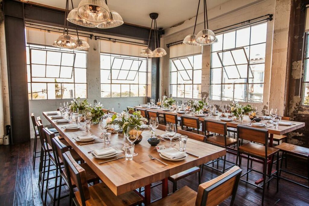 Open space with two long dining tables and big windows pouring in bright light