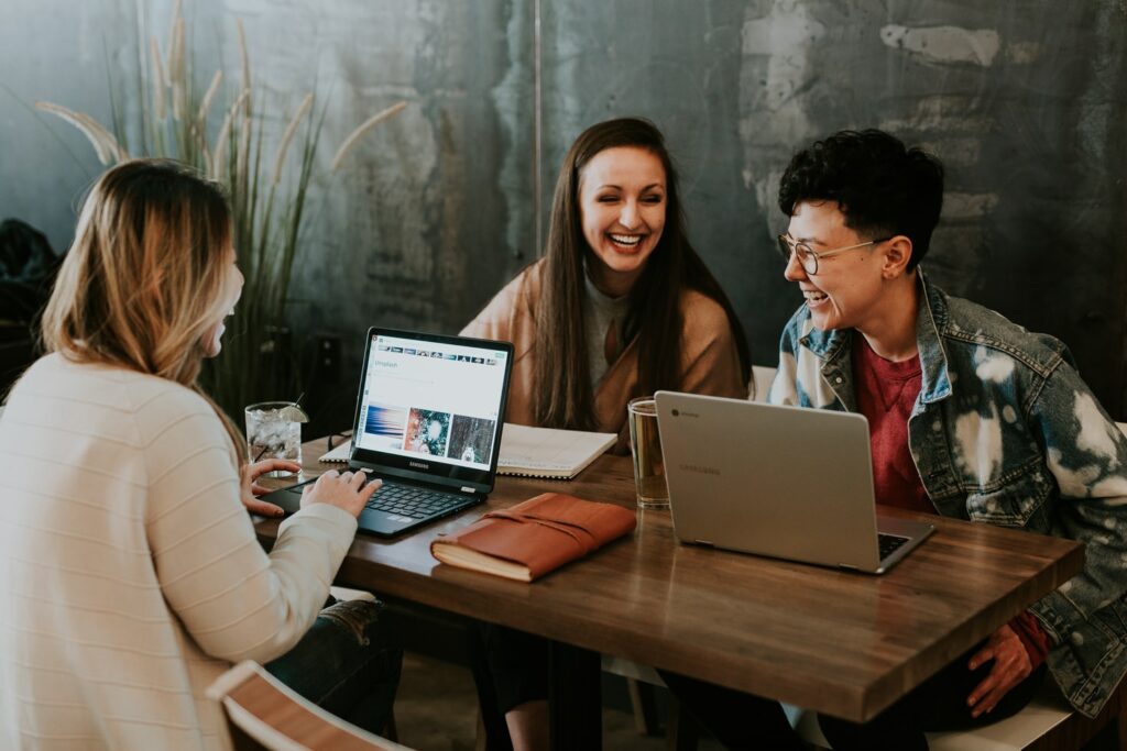 A group of three people on laptops laughing