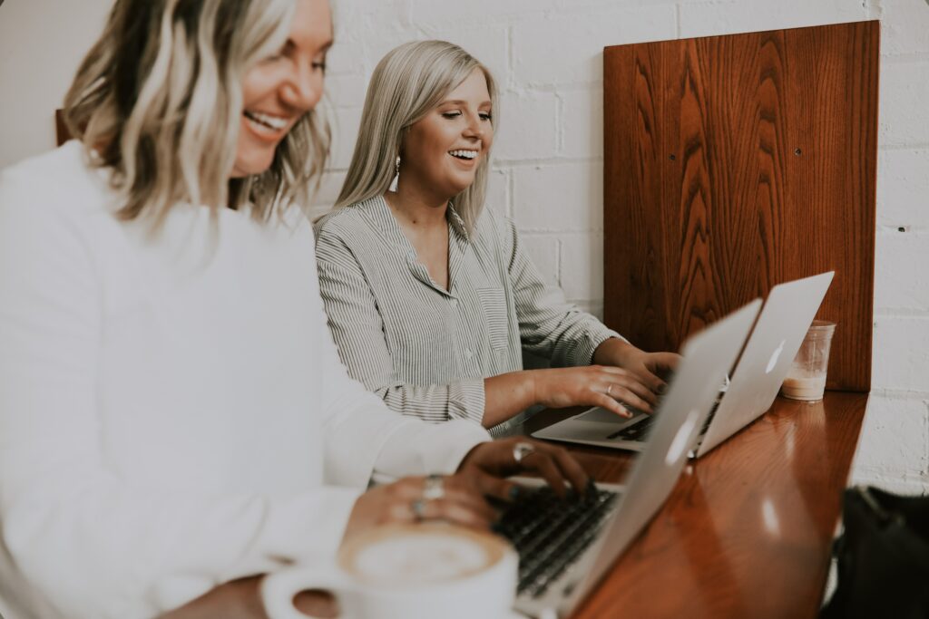 Two women on laptops laughing 