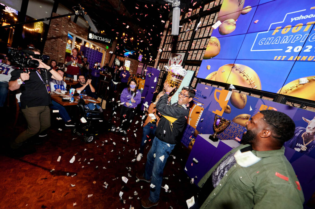 A man holding a trophy with confetti raining down