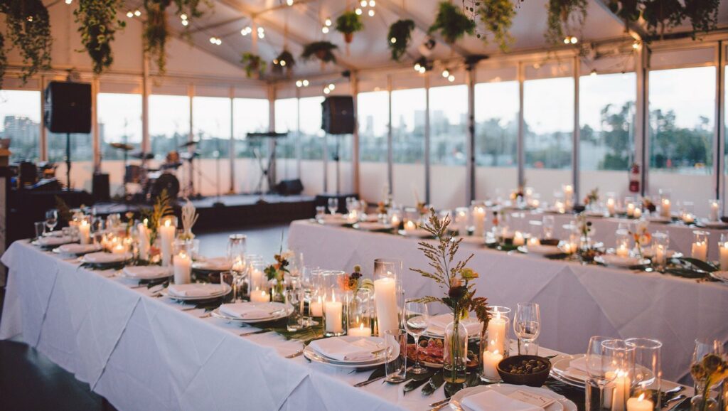 An enclosed rooftop bar with tables set with flowers, glassware, and candles