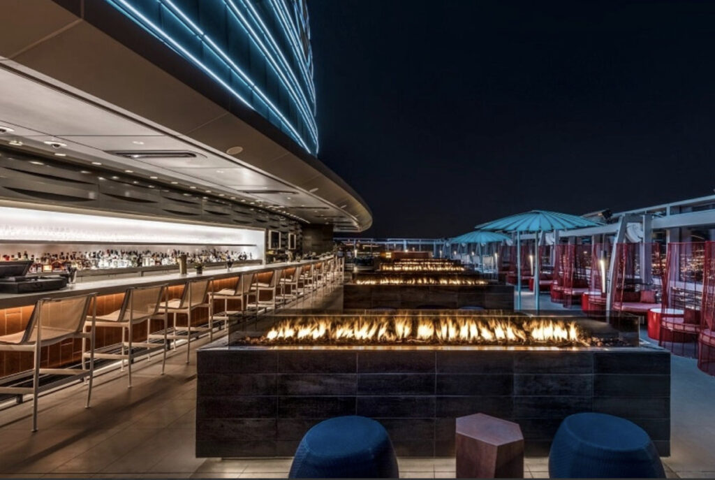 Rooftop of Spire 73 in Los Angeles at night with multiple modern fire bits