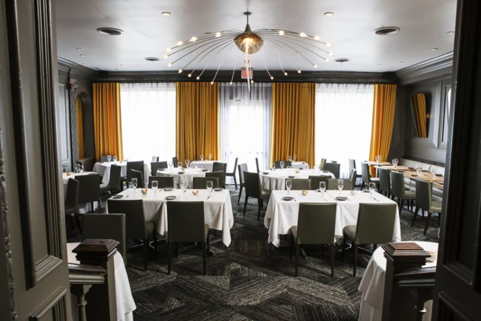 Dining space at Aria in Atlanta with white table clothes and yellow hangingcurtains