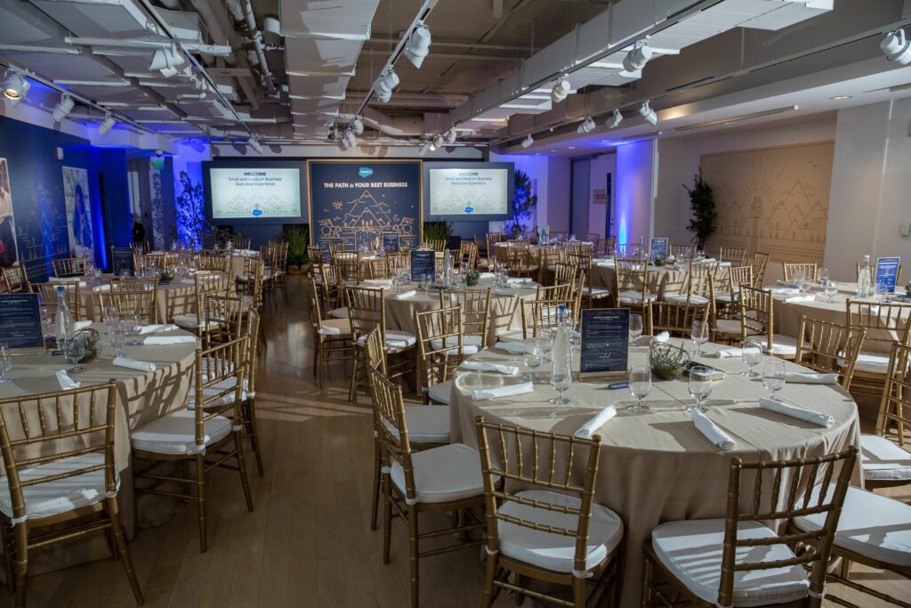 Large room with tables and chairs set up for a Salesforce event